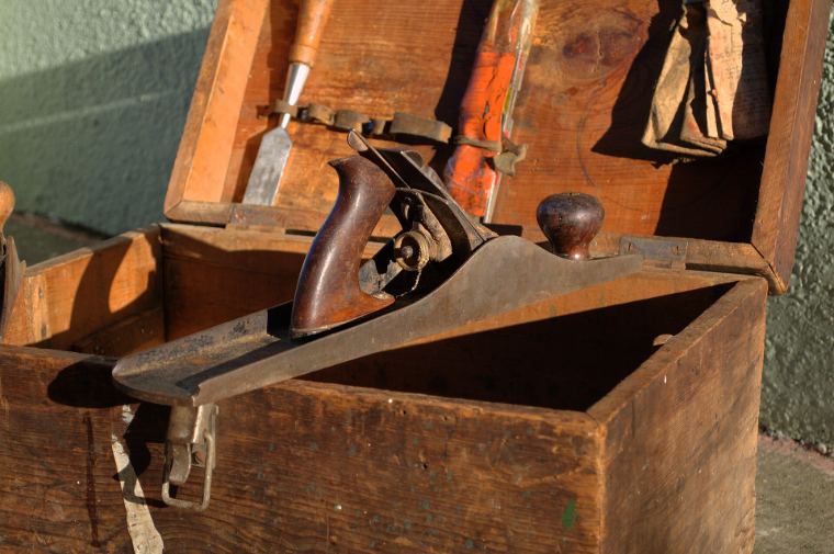 An old wooden hand plane resting in a tool chest