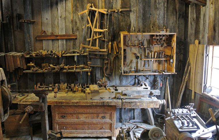 A wood workshop with hand tools on the wall and a bench full of clamps